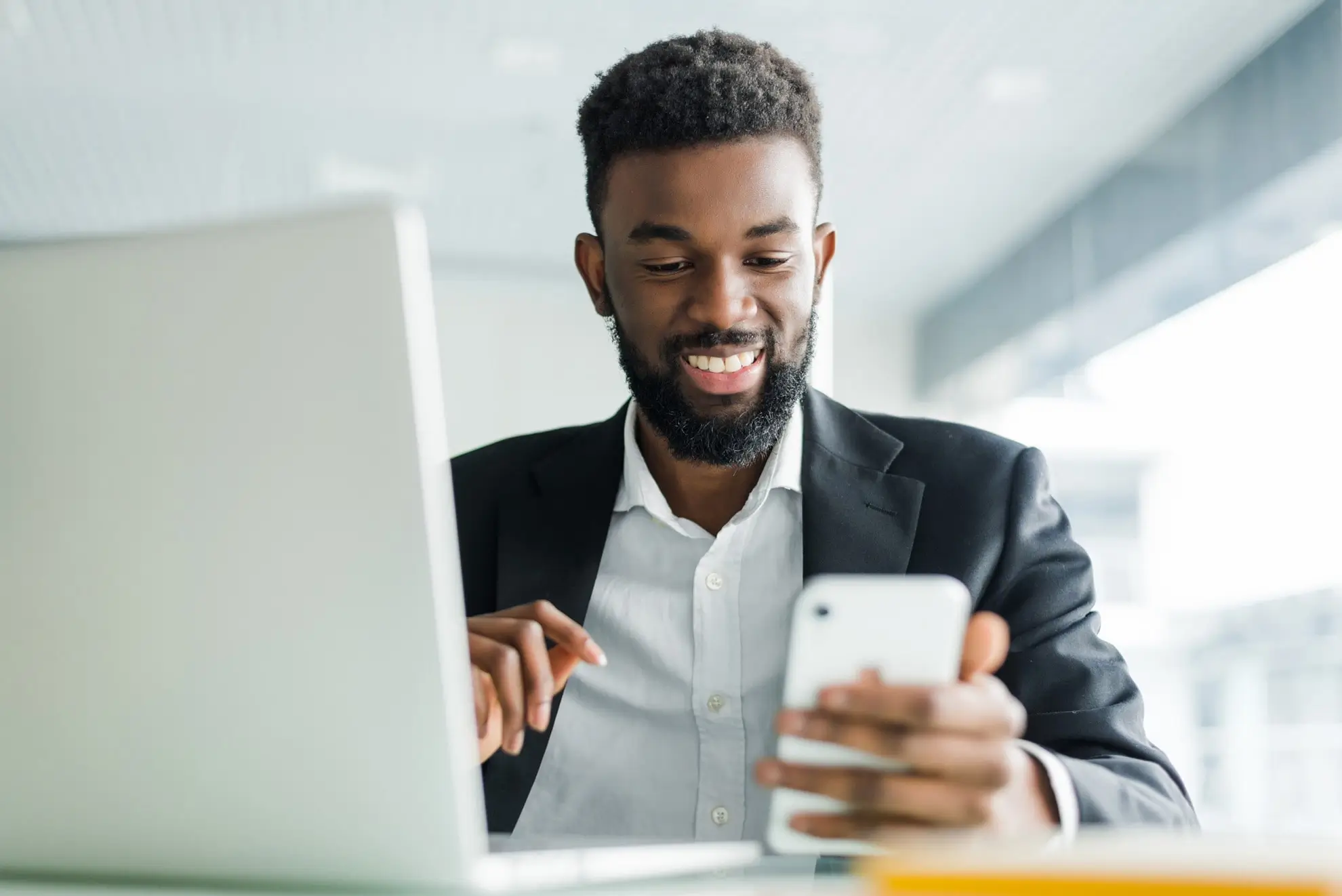 Empreendedor de terno em escritório com celular na mão